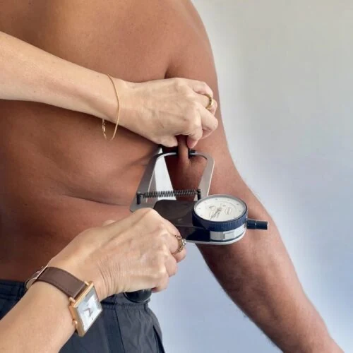 Medición de un pliegue cutáneo con calibre durante una evaluación antropométrica
